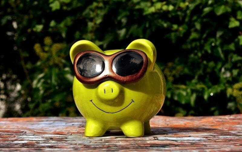 A smiling green piggy bank wearing sunglasses